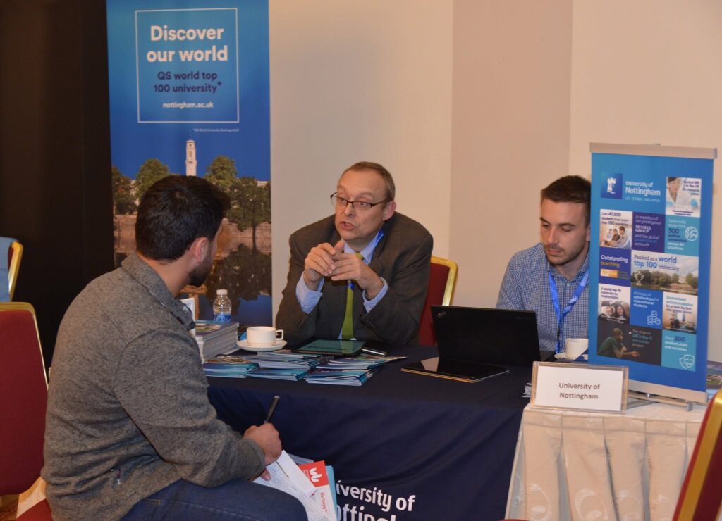 Students and university representatives in conversation at a busy stand